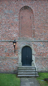De tegenwoordige hoofdingang aan de westkant van de kerk met daarboven een dichtgemaakt raam. Foto: ©Harm Hillinga, 2 dec. 2012.