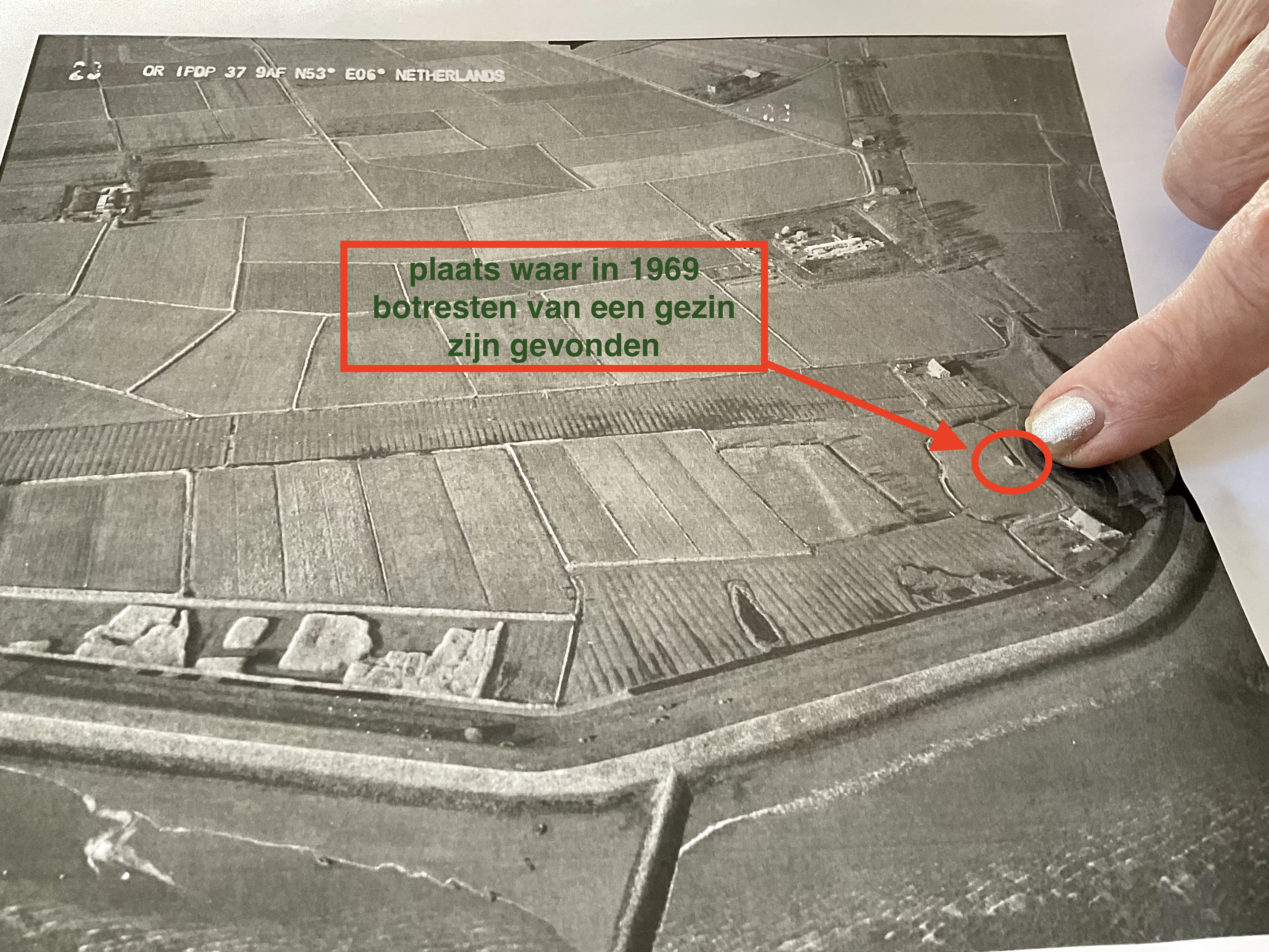 Hebeltje Duursema wijst in april 2022 op een luchtfoto de plaats aan waar een boerderijtje heeft gestaan en waar zij de botresten van een gezin hebben gezien. Foto: april 2022, ©Jur Kuipers.