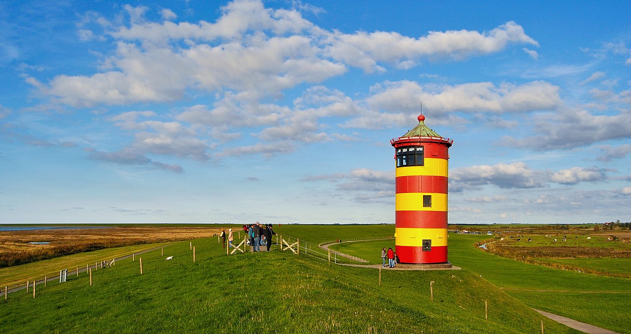 De vuurtoren van Pilsum (Dld) is een vuurtoren die gebouwd is als onderdeel van het lichtenplan voor de Beneden-Eems. De ijzeren vuurtoren is 11 meter hoog en dateert uit 1891. Hij werd in 1915 buiten gebruik gesteld. De fundering is in de zeedijk gebouwd en de toren is geel-rood geschilderd. Hij is bekend van de reclame voor een regionaal biermerk, en omdat hij locatie is geweest voor de film 'Otto - Der Außerfriesische' (1989) en voor de Tatort-aflevering 'Sonne und Sturm' (2003) met Maria Furtwängler. Sinds 2004 is de vuurtoren ook als trouwlocatie in gebruik. Foto: 17 oktober 2010. Licentie: Creative Commons Naamsvermelding-Share Alike 3.0 de.