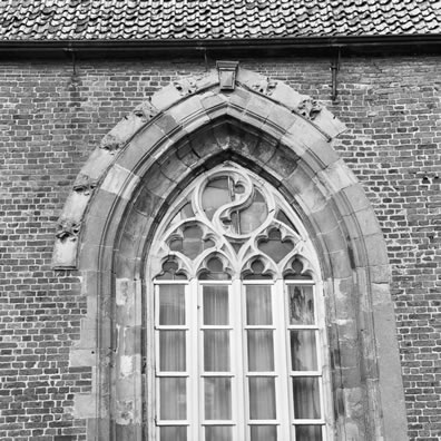 De bovenkant van een raam aan de zuidgevel van de kerk boven de ingang voor de laatste restauratie. Foto Wikipedia.