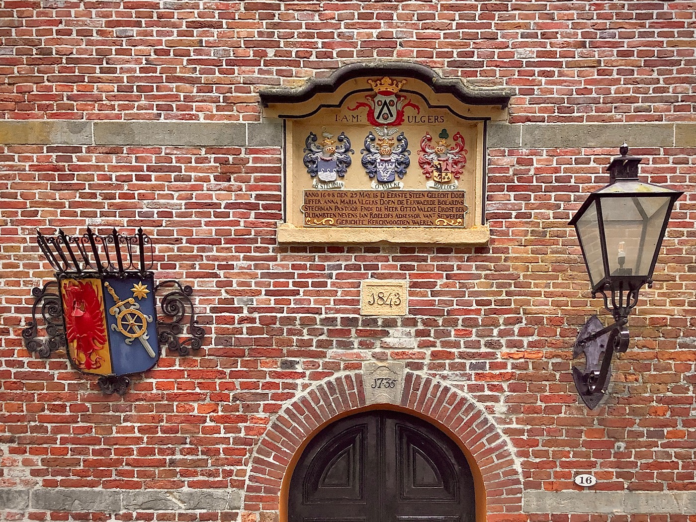 De toegang tot de kerk onder de toren met een gekleurde gedenksteen van de familie Ulgers boven de ingang met daaronder het jaartal 1843. Boven de ingang zien we het jaartal 1733. Foto: ©Jur Kuipers.
