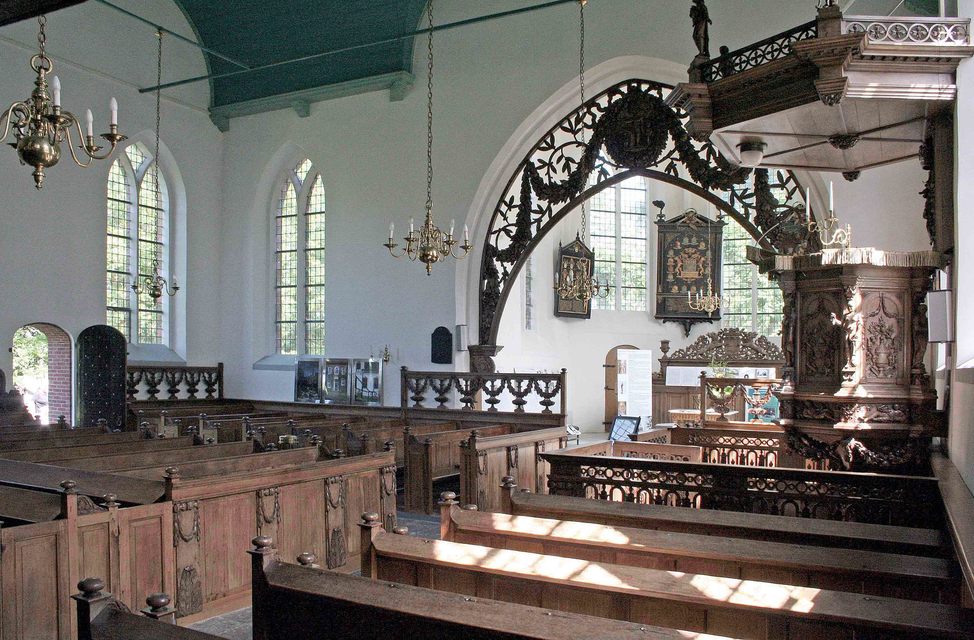 Interieur met zicht op de zitbanken, het koor en de triomfboog, met rechts de preekstoel. In het koor zien we ook de toegangsdeur van de borgheren en -dames.