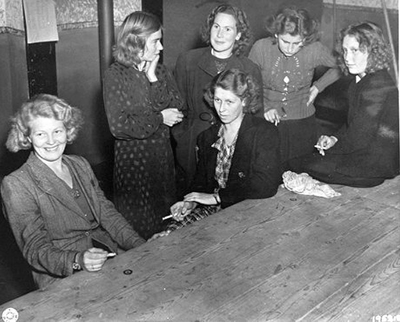 Nederlandse vrouwen die een relatie hebben onderhouden met een Duitser, door het verzet gearresteerd, wachten op 18 september 1944 in Grave op het publiekelijk kaalscheren. Daarna zullen ze door de straten moeten marcheren